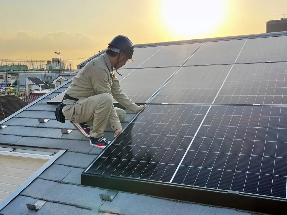 屋根の上で太陽光パネルを設置する施工スタッフ