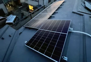 4_5 - 東京都の補助金制度を活用した太陽光・蓄電池・V2H設置サポート|ソルト公式 Rooftop solar panel array installed on a flat urban roof, with surrounding buildings in view.