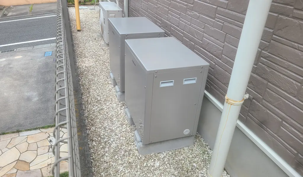 外壁沿いの砂利の通路に置いたニチコンの蓄電池ユニット(町田市)